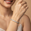 Close-up of a woman's hand wearing a diamond bracelet on a beige background