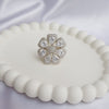 Silver floral ring with clear gemstones on a white beaded surface
