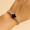 Bracelet with black flower design and clear stones on a wrist against a beige background